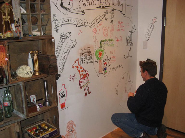 Ken adds his touch to the white board wall