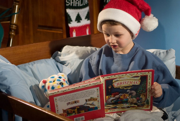 Two brothers reading a christmas book in bed