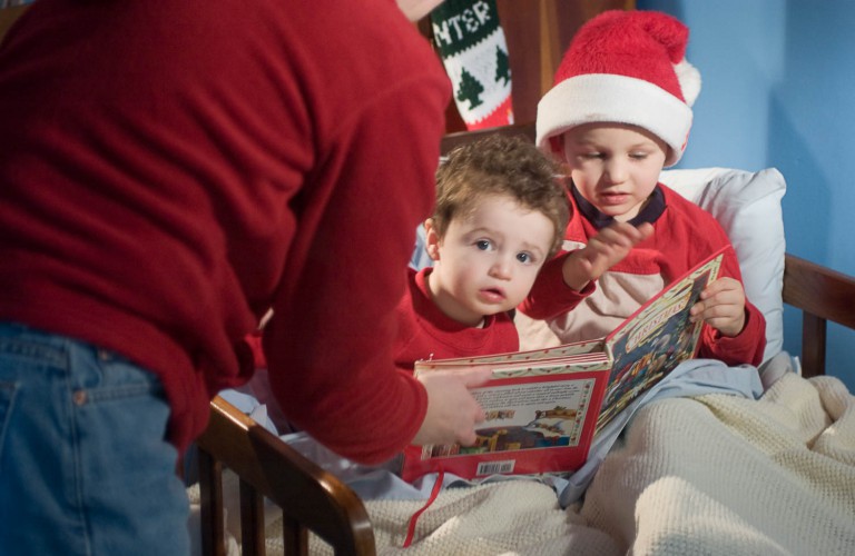 Two brothers reading a christmas book in bed