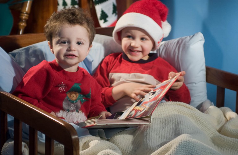 Two brothers reading a christmas book in bed