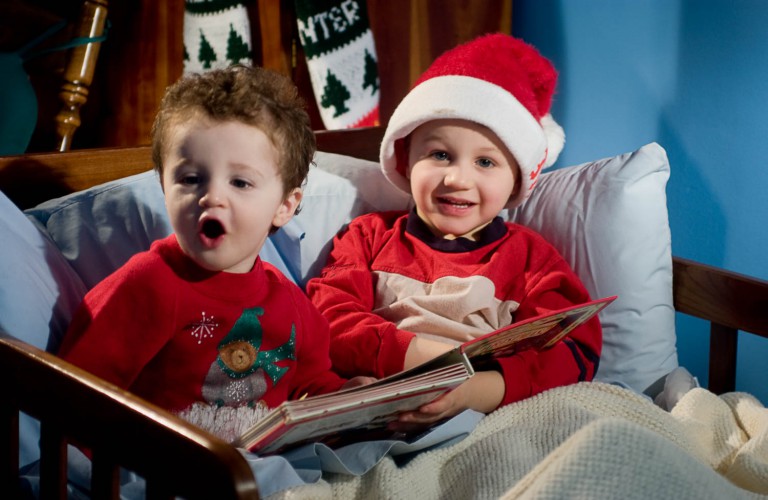 Two brothers reading a christmas book in bed