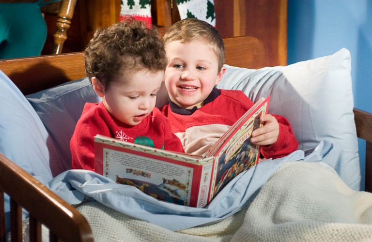 Two brothers reading a christmas book in bed